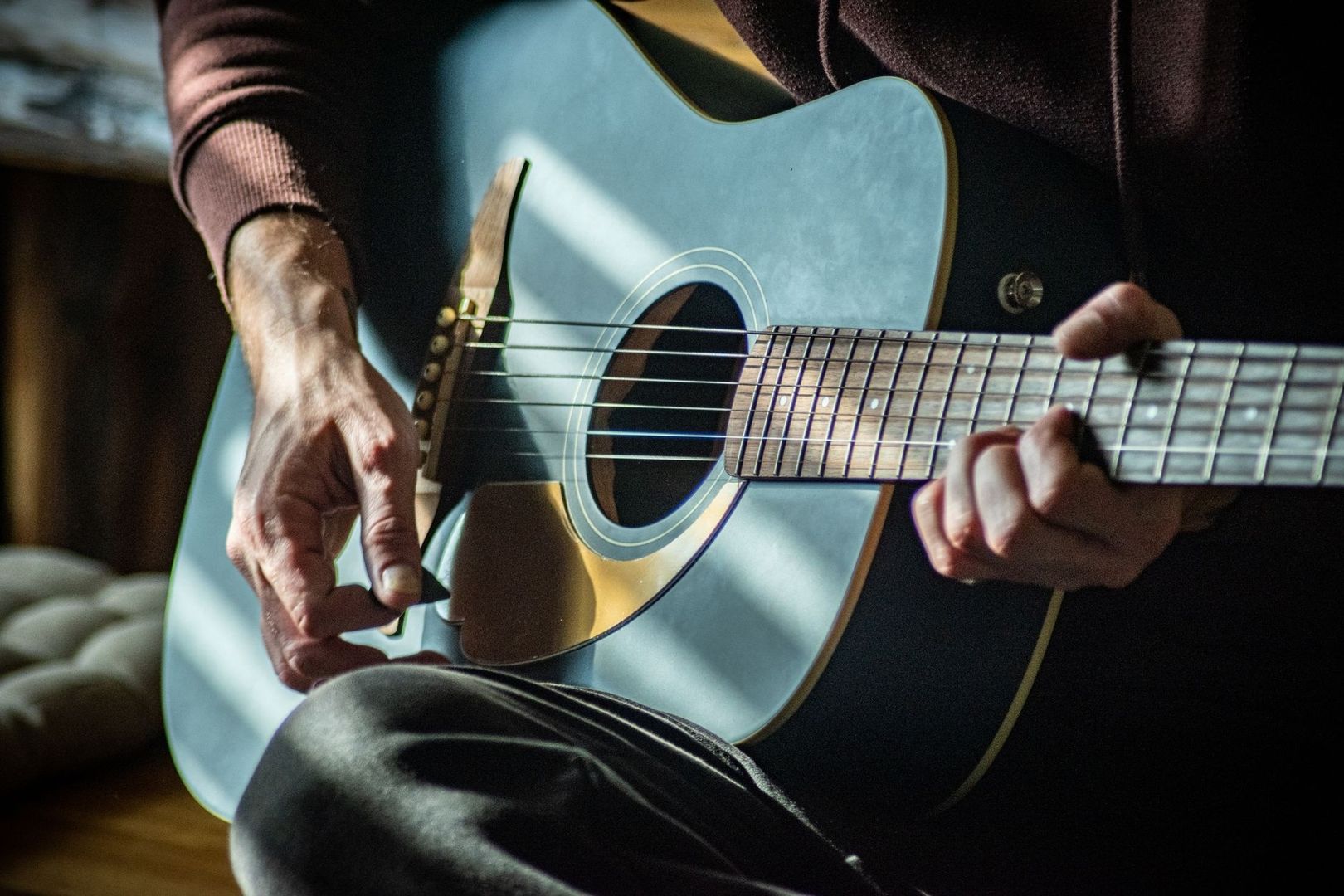 Close-up van een muzikant die een akoestische gitaar bespeelt